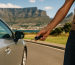 Close-up of a person holding car keys in front of a silver car with Table Mountain in the background, symbolising vehicle ownership in Cape Town.